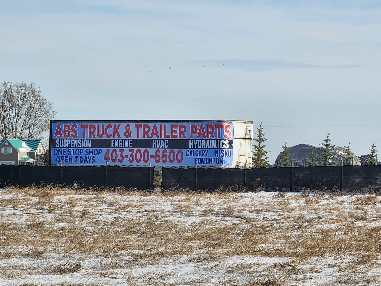 Full-length ABS Truck and Trailer Parts banner on the side of a trailer by the highway