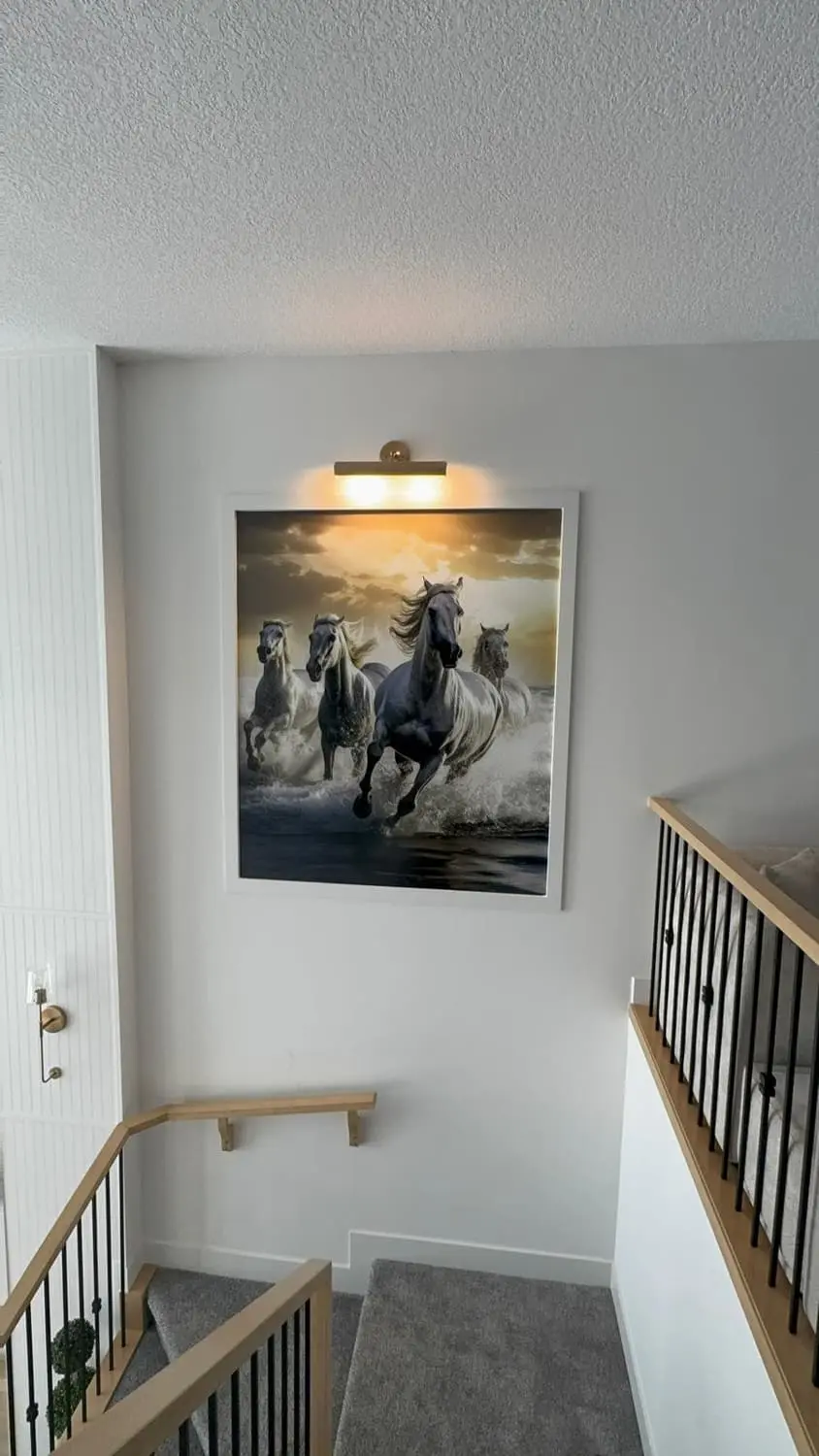 Framed print of galloping horses installed on a stairwell wall